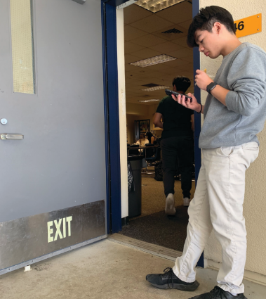 Nathan Do checks his phone outside classroom L-46 during lunch.