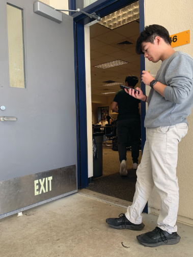 Nathan Do checks his phone outside classroom L-46 during lunch.